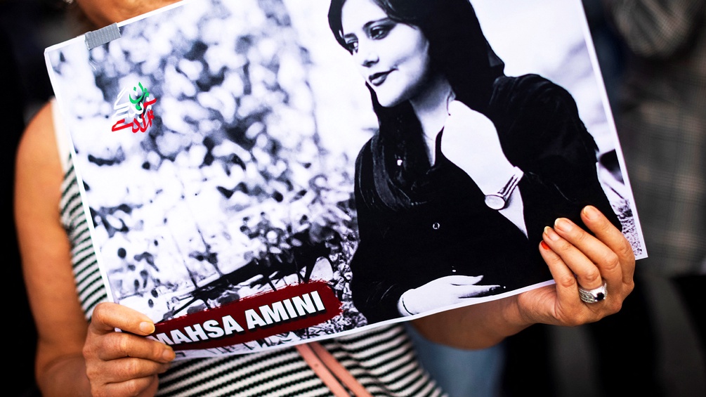 Ein Frau hält ein Bild von Mahsa Amini