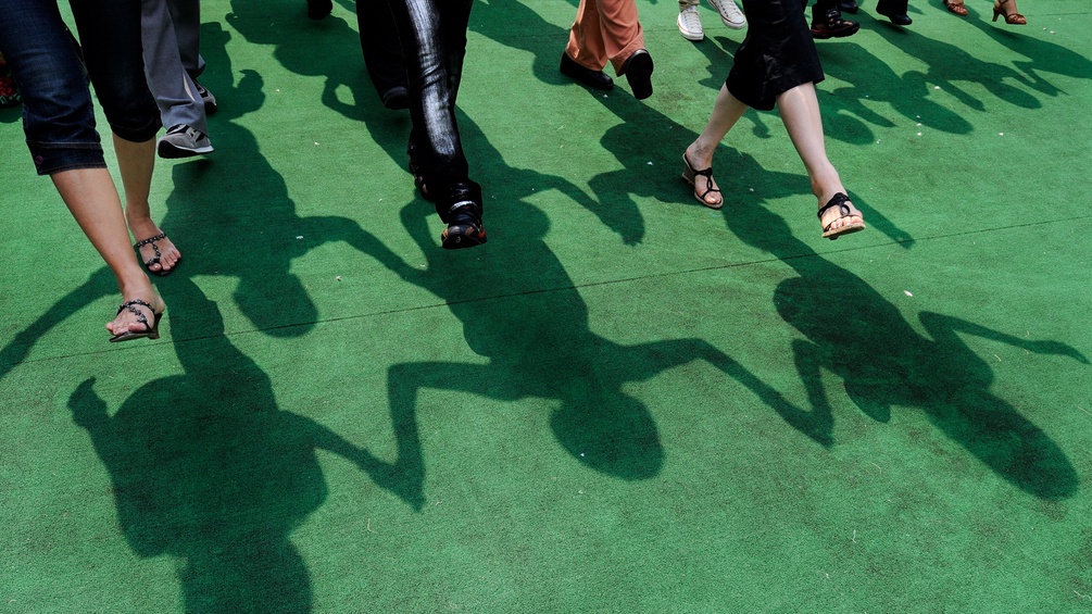 Menschen gehen gemeinsam über einen grünen Teppich.