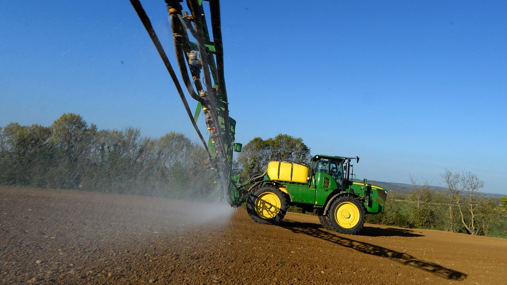 Traktor auf dem Feld versprüht Pestizide