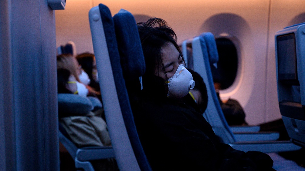 Eine Frau schläft im Flugzeug.