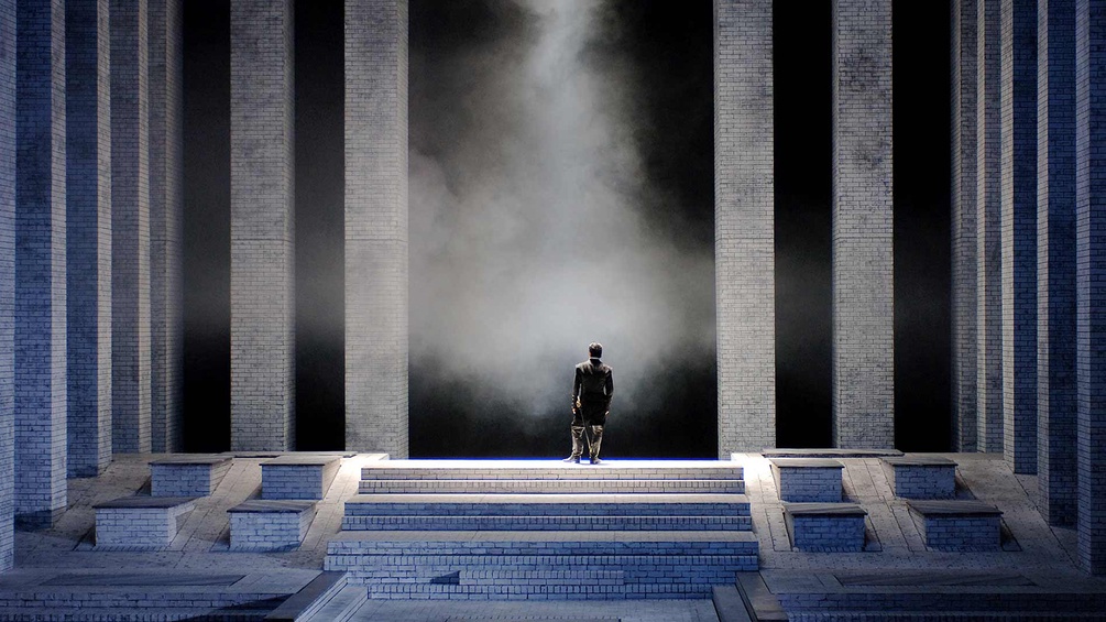 Mann steht alleine auf einer Bühne, Ausschnitt "Don Carlo"