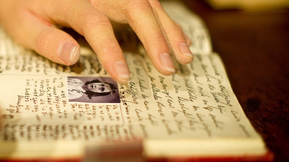 Eine Wachsfigur von  Anne Frank, die in ihrem Tagebuch schreibt