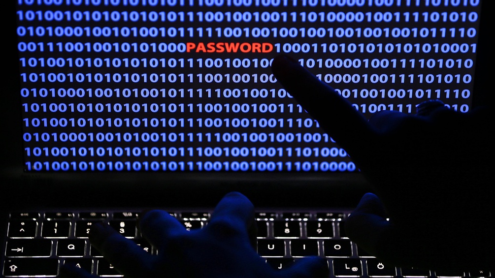  Ein Finger zeigt auf das Wort «Password», das zwischen Zeichen des Binärcode auf einem Computerbildschirm steht.