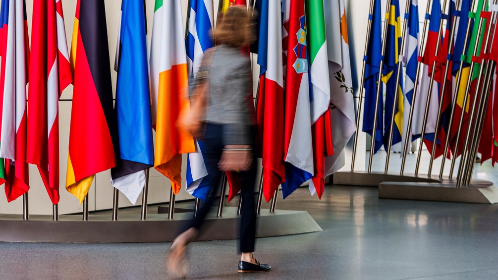 Frau geht vor europäischen Fahnen