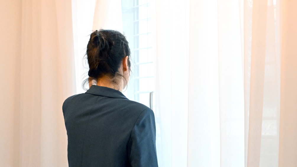 Frau schaut aus dem Fenster, Vorhang