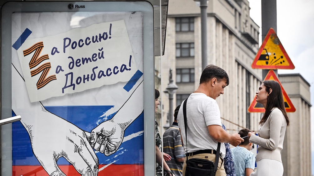 Russische Plakate mit Z-Symbol hängen an der Bushaltestelle.