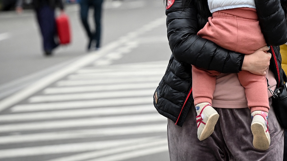 Ukrainische Frau hält ihr Kind auf dem Arm, Zebrastreifen