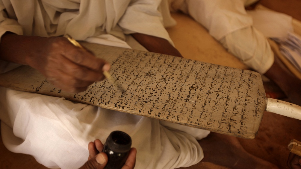 Ein Sufi Lehrer schreibt auf ein Holzboard.