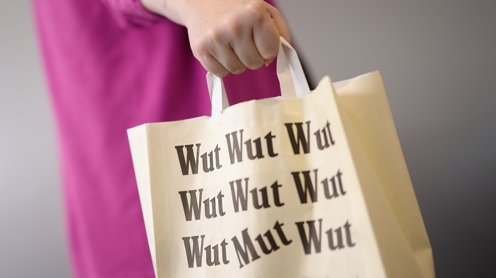 Eine Frau mit einer Papiertragetasche mit der Aufschrift "Mut"