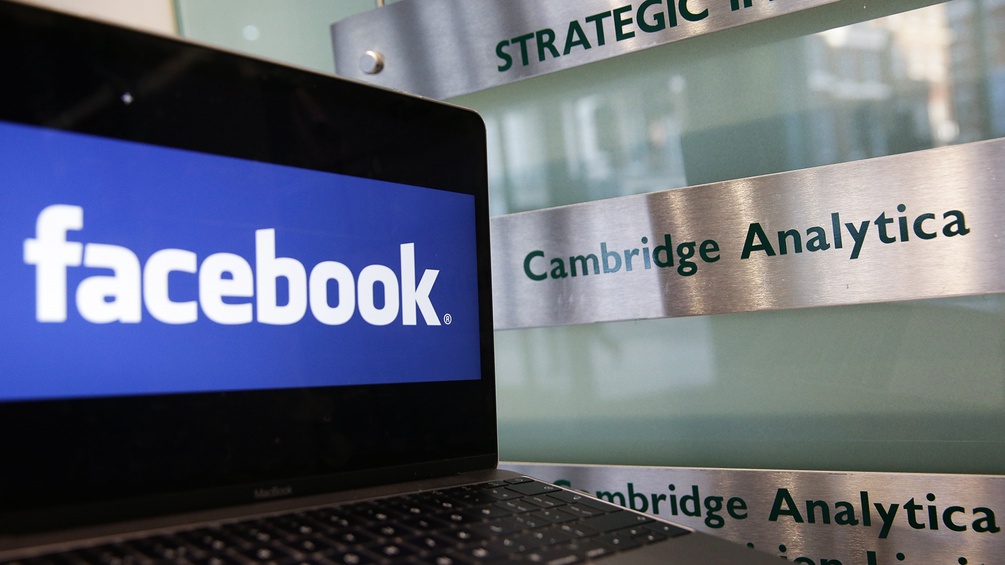 AFP/DANIEL LEAL-OLIVAS Ein Laptop mit Facebook-Logo neben einem "Cambridge Analytica"-Schild