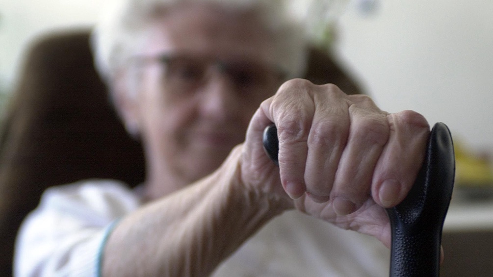 Eine Pensionistin stützt sich in einem Altersheim an ihren Gehstock.