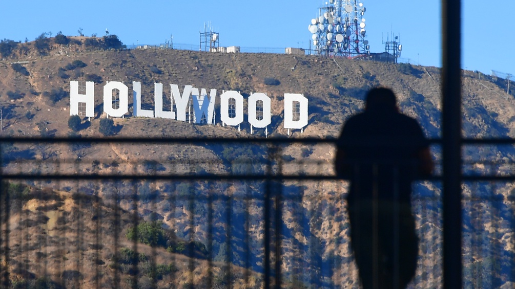 Mann steht hinter Gitter vor dem Hollywood Schriftzug