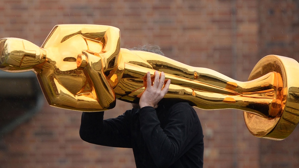 Ein Mann trägt eine Oscar-Statue