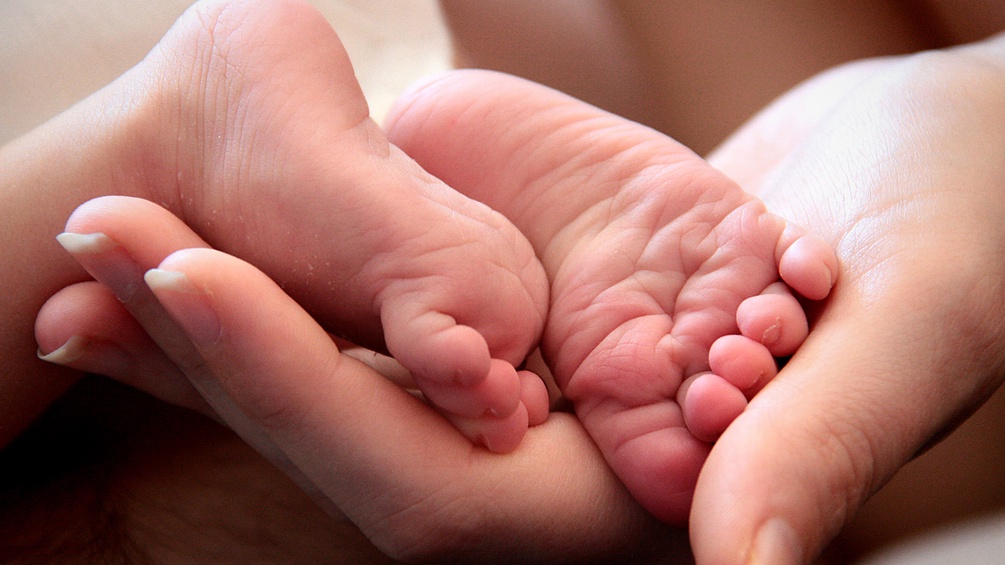 Frauenhand hält Babyfüße