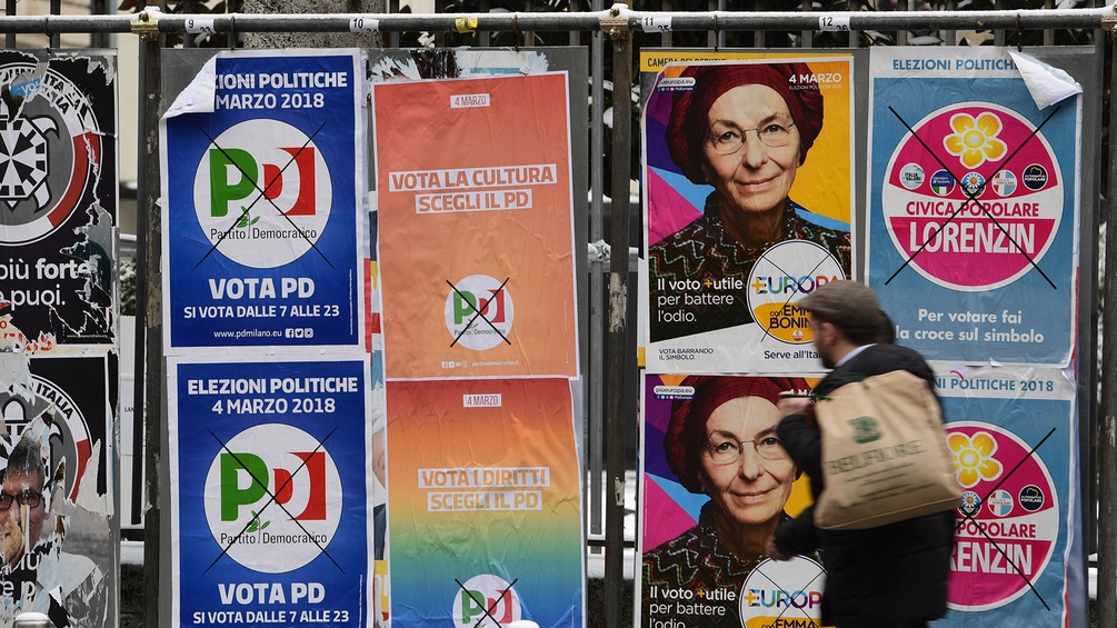 Mann geht an Wahlplakaten in Italien vorbei
