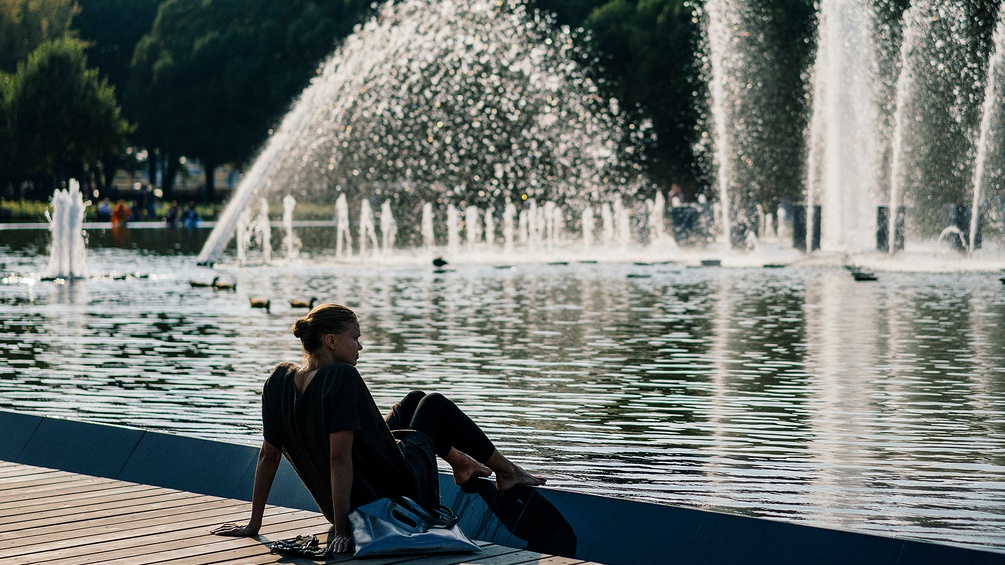 Ein Frau sitzt vor einem Teich im Gorki Park