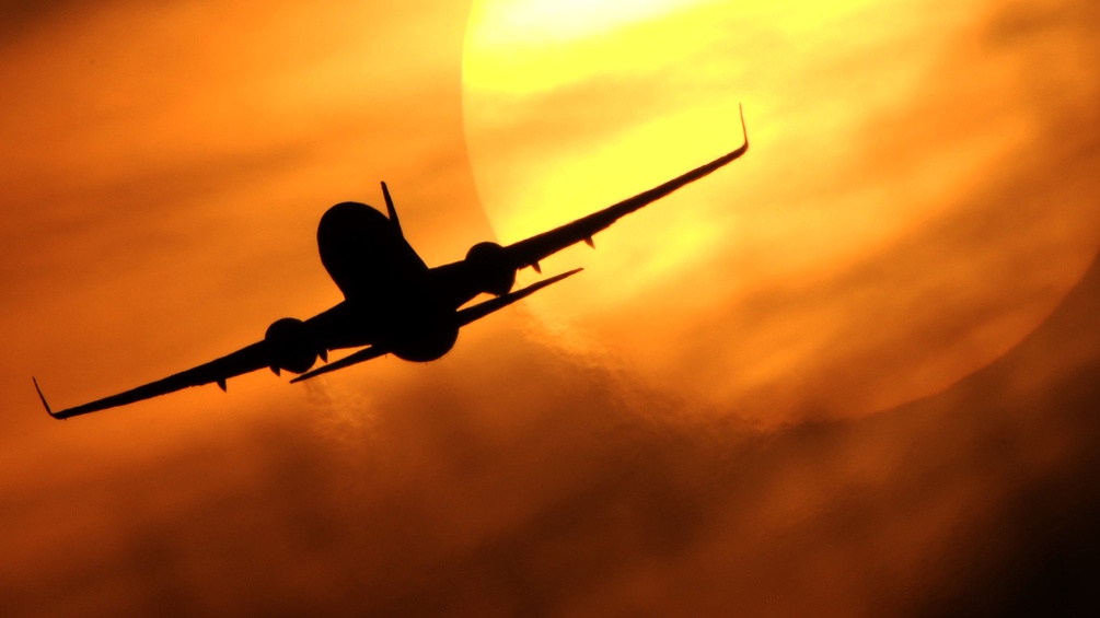 Ein Flugzeug startet vor der untergehenden Sonne