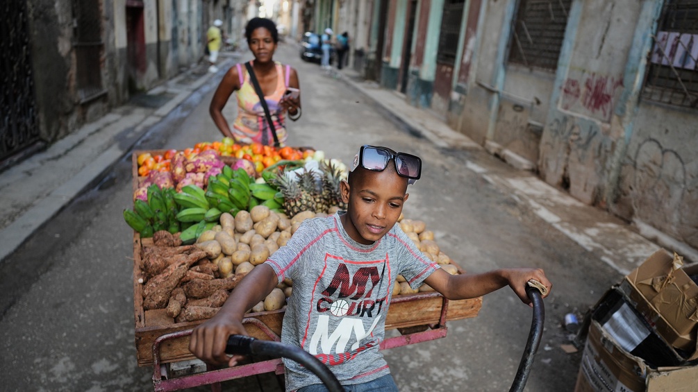 Alltag in Kuba: Kind mit Frau transportieren Gemüse