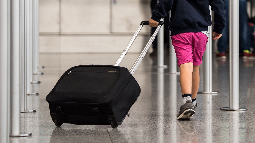 Kind mit Koffer auf Reisen
