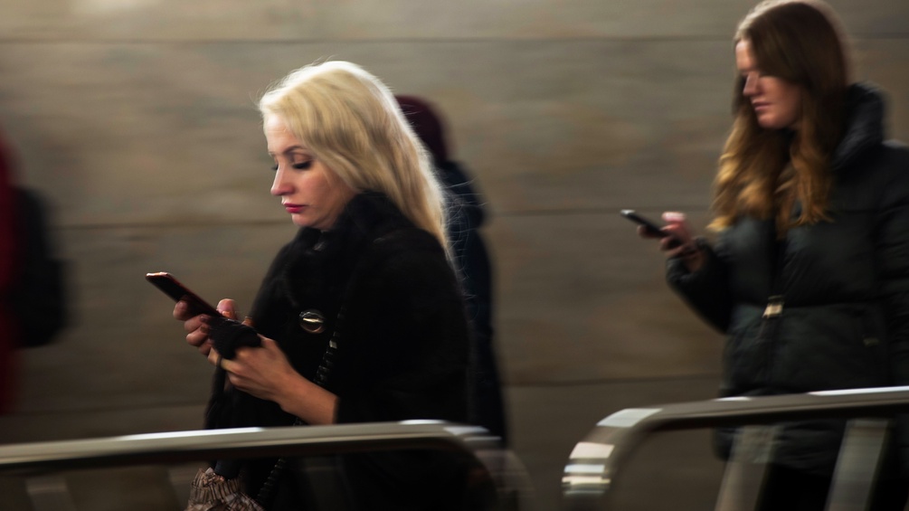 Zwei Frauen starren auf ihr Handy in einer Ubahnstation