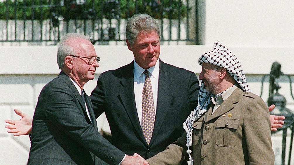 Yitzhak Rabin und PLO-Chef Yassir Arafat schütteln sich die Hände, in der Mitte Bill Clinton