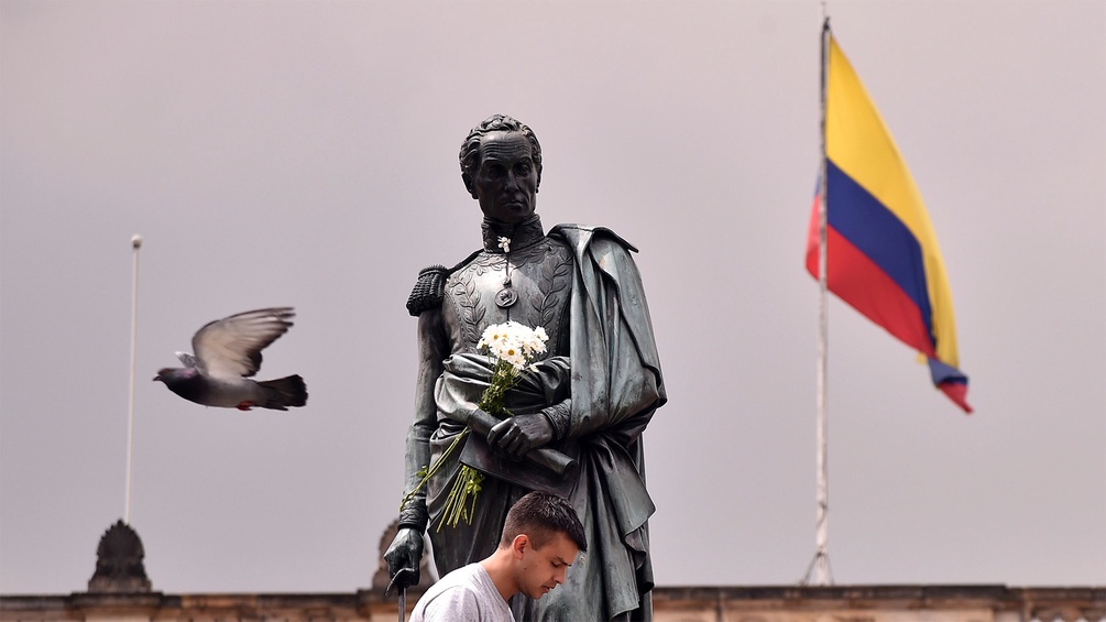 Straßenszene in Kolumbien mit Flagge, Taube und Statue