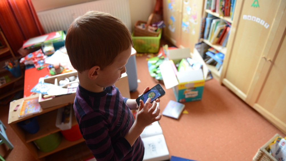 Kind spielt mit Smartphone im Kinderzimmer
