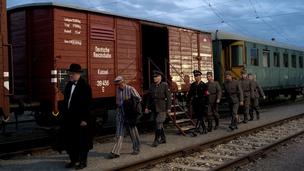 Szenenfoto mit historischen Zügen, KZ-Häftlingen und Soldaten