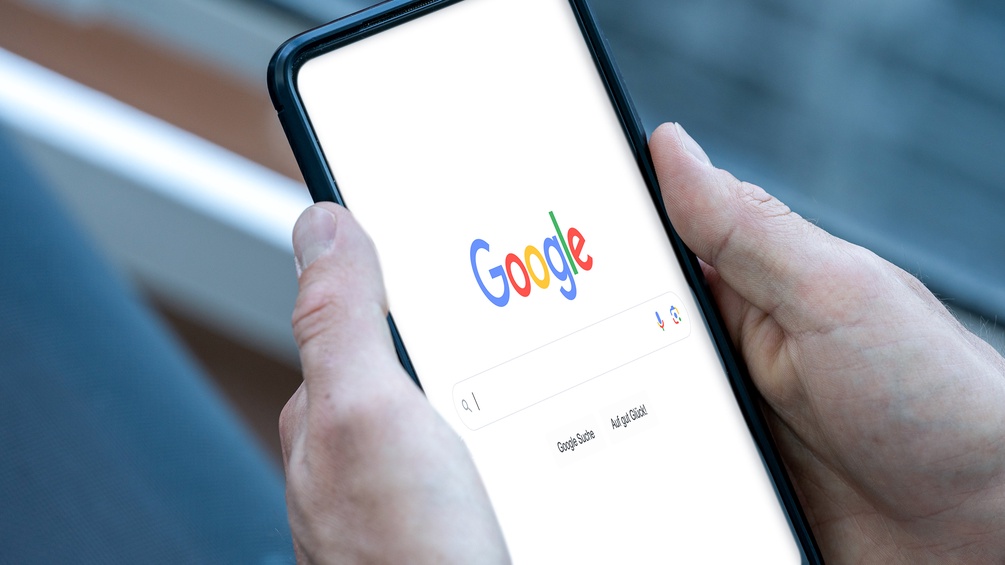 Mann hält Smartphone in Händen - Google Searchbar