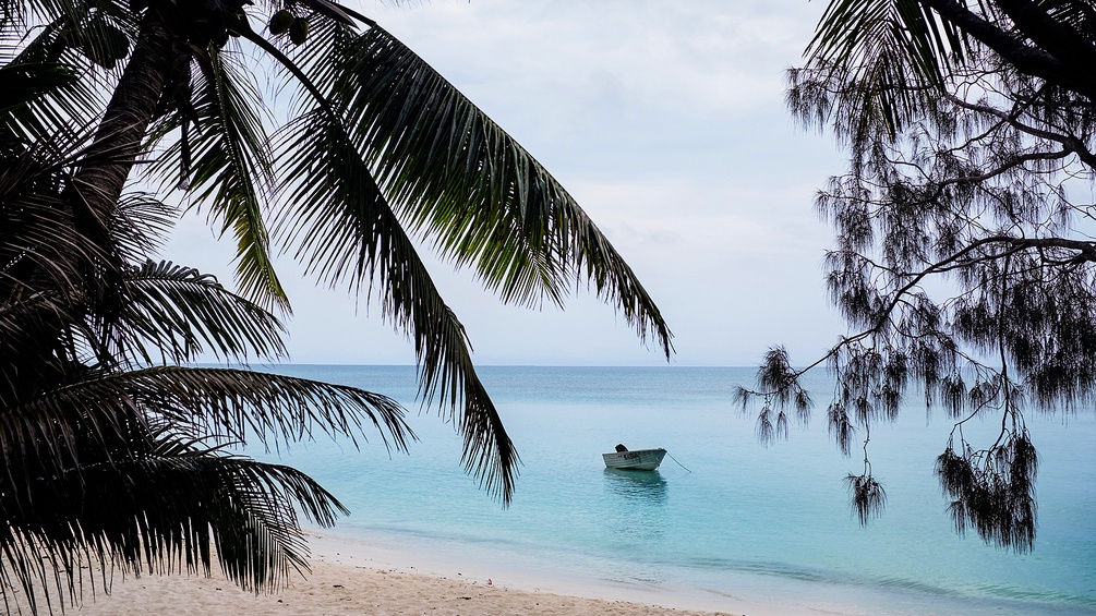 Ein kleines Boot liegt vor einem tropischen Strand