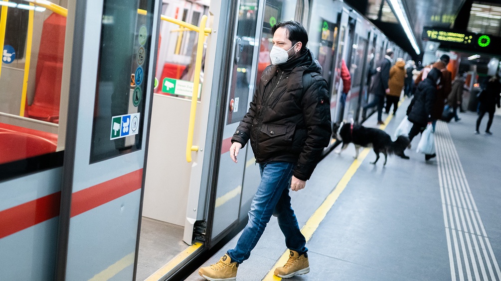 Mann in der Ubahn trägt eine Maske.