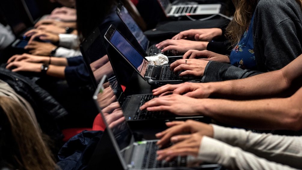 Studenten sitzen nebeneinander an ihren Laptops