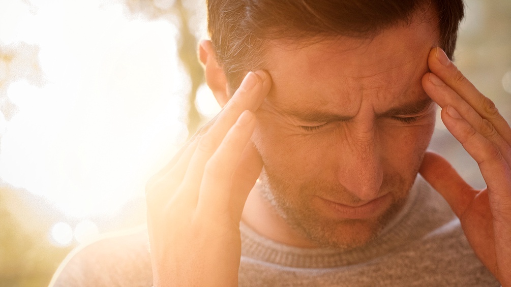 Mann greift sich schmerzverzerrt an die Schläfen - Migräne