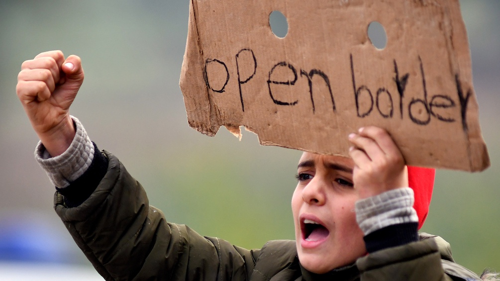 Protestierendes Kind mit einem Karton mit der Aufschrift "Open Border"
