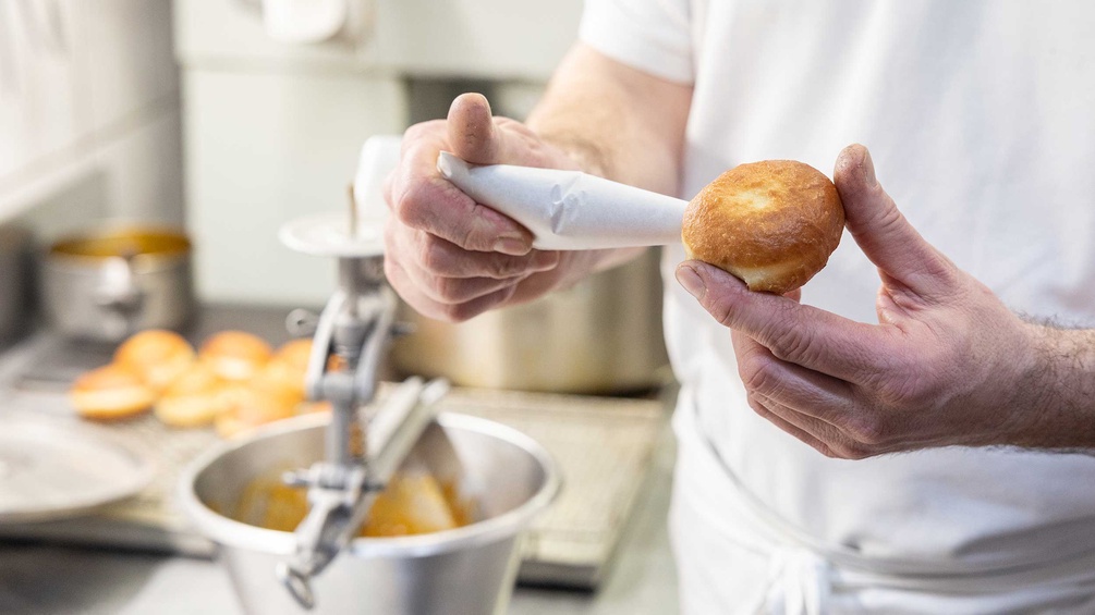 Bäcker füllt einen Krapfen