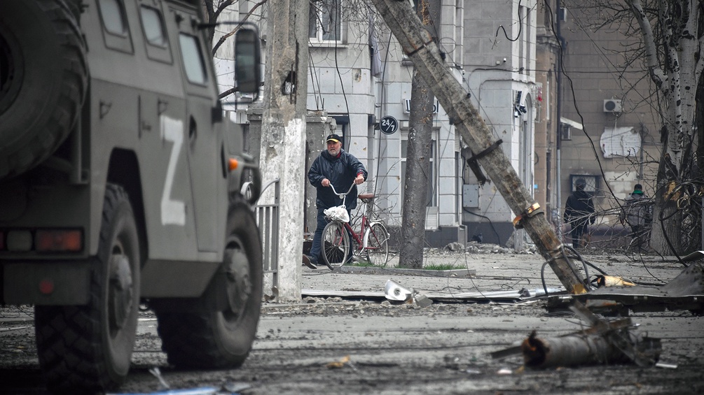Ein Mann schiebt sein Fahrrad im Zentrum von Mariupol, Ukraine.