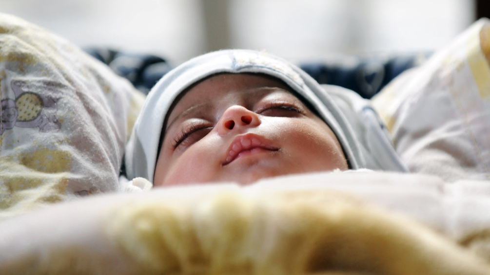 Eine Neugeborene schläft in ihrem Bett