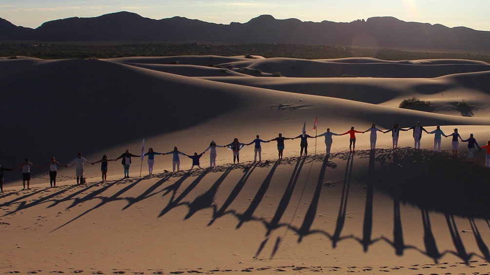 Menschen halten sich an der Hand und stehen in der Wüste