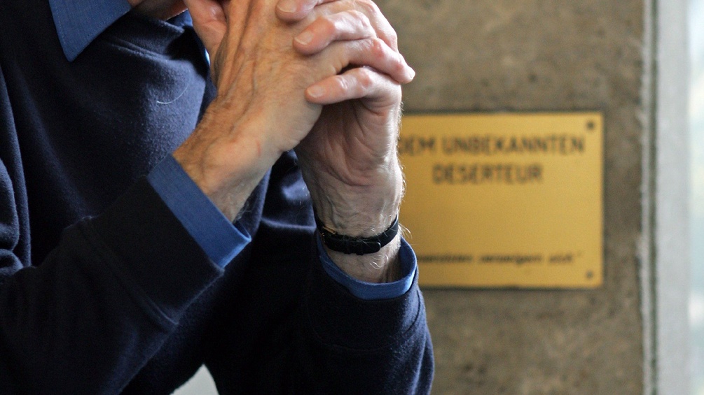 Ein Mann mit verschränkten Händen vor einem Deserteursdenkmal