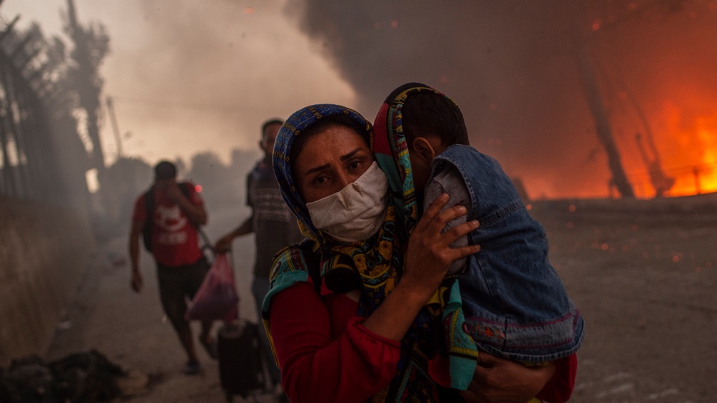 Frau mit Kind flüchtet vor dem Feuer in Moria