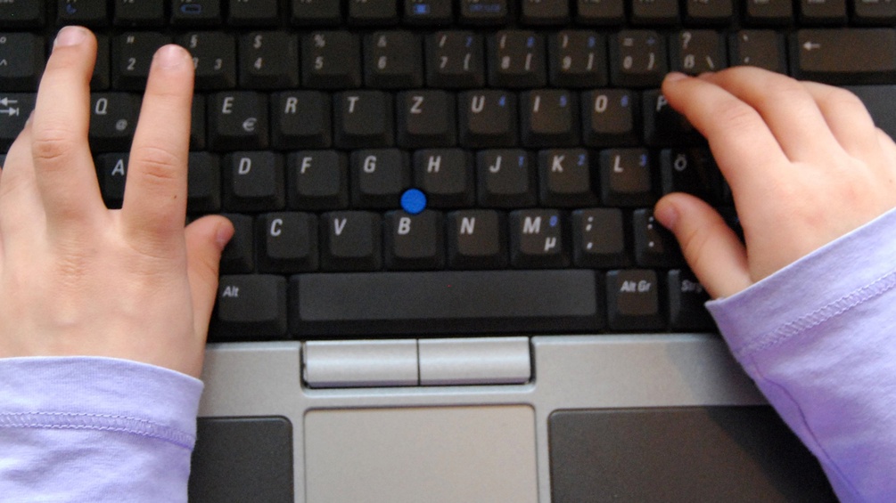 Kinderhände auf Laptoptastatur