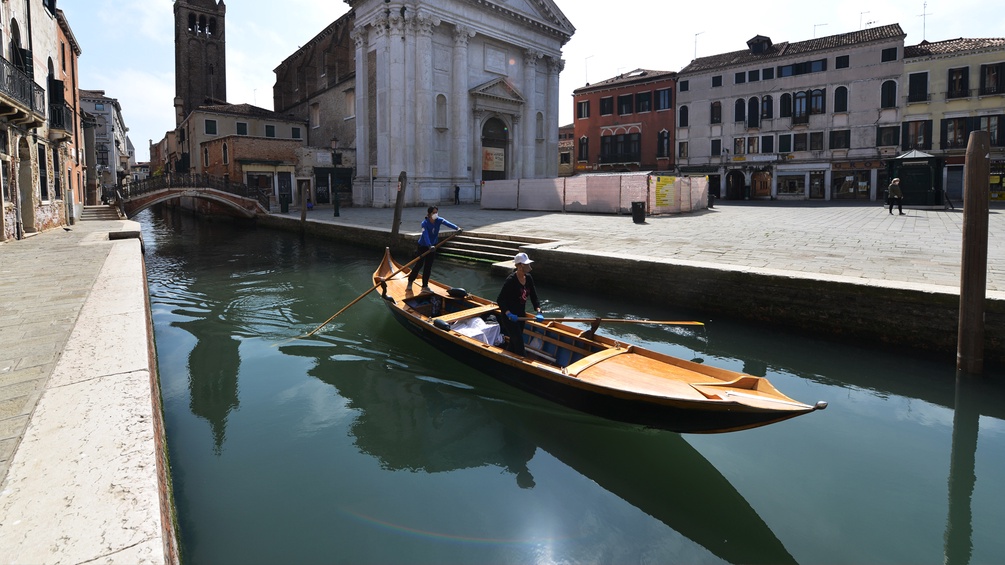 Ein Boot fährt durch einen Kanal in Venedig neben einem Platz ohne Touristen.