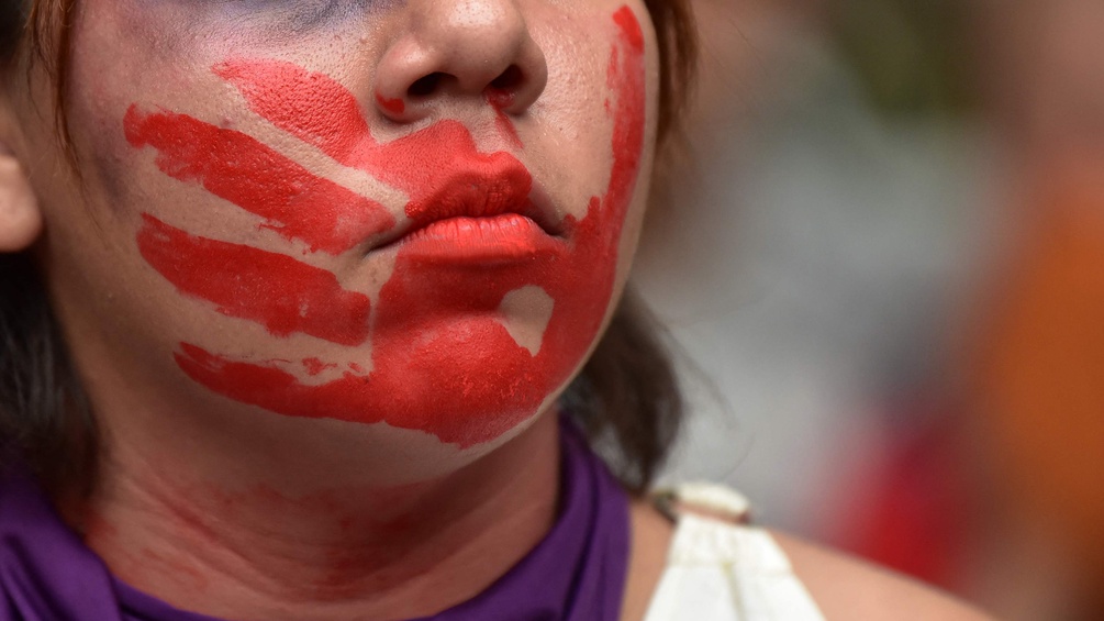 Demonstrantin mit aufgemalter, roter Hand im Gesicht