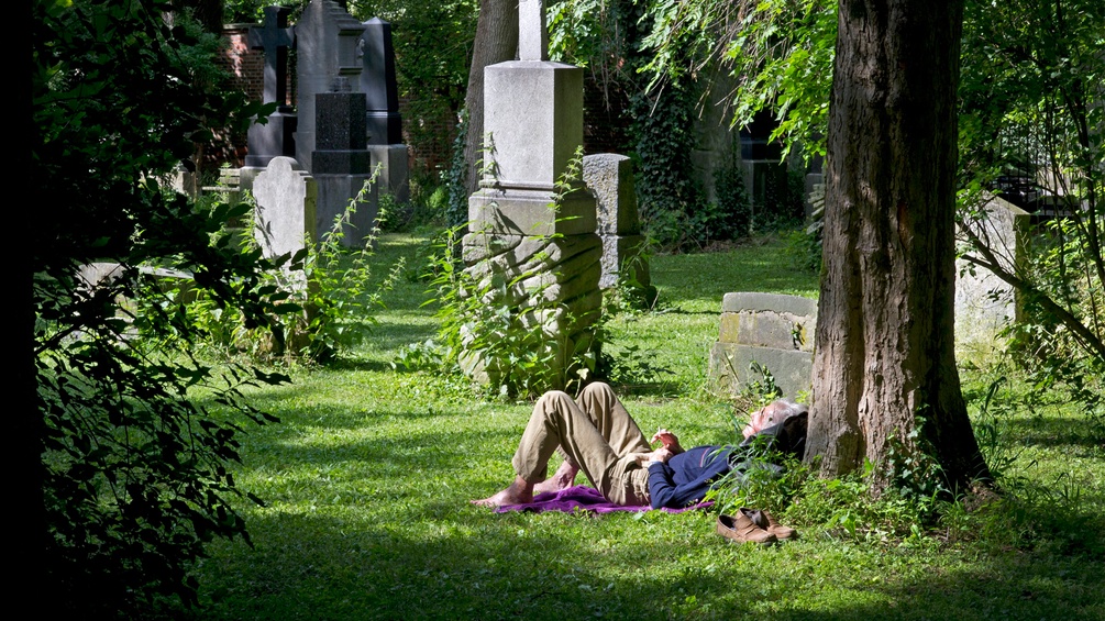 Ein Mann ruht sich am Friedhof aus.