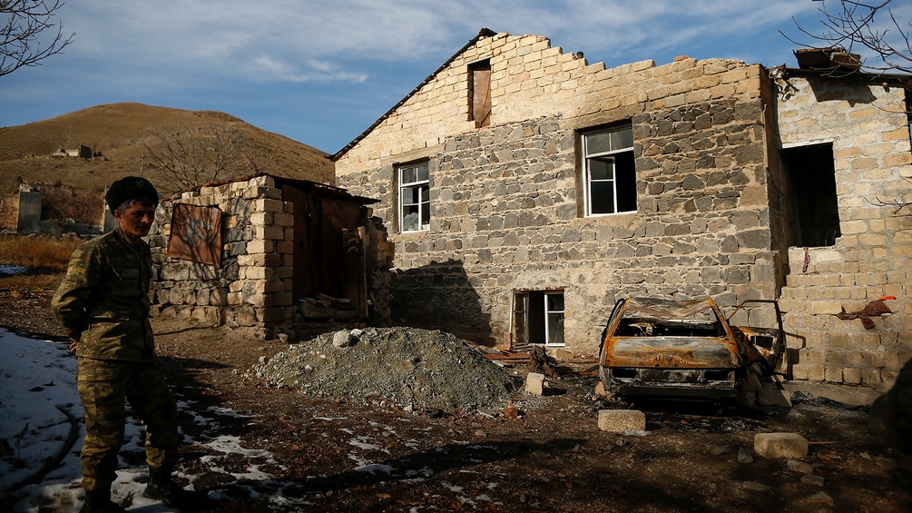 Aserbaidschanischer Soldat vor einem zerstörten Haus in Armenien