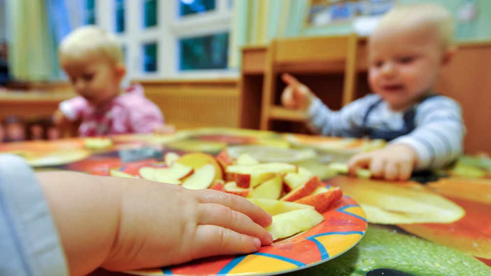 Kleinkinderhand mit Apfelspalten