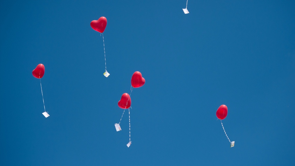 Liebesbriefe angebunden an herzförmige Ballons steigen in den Himmel
