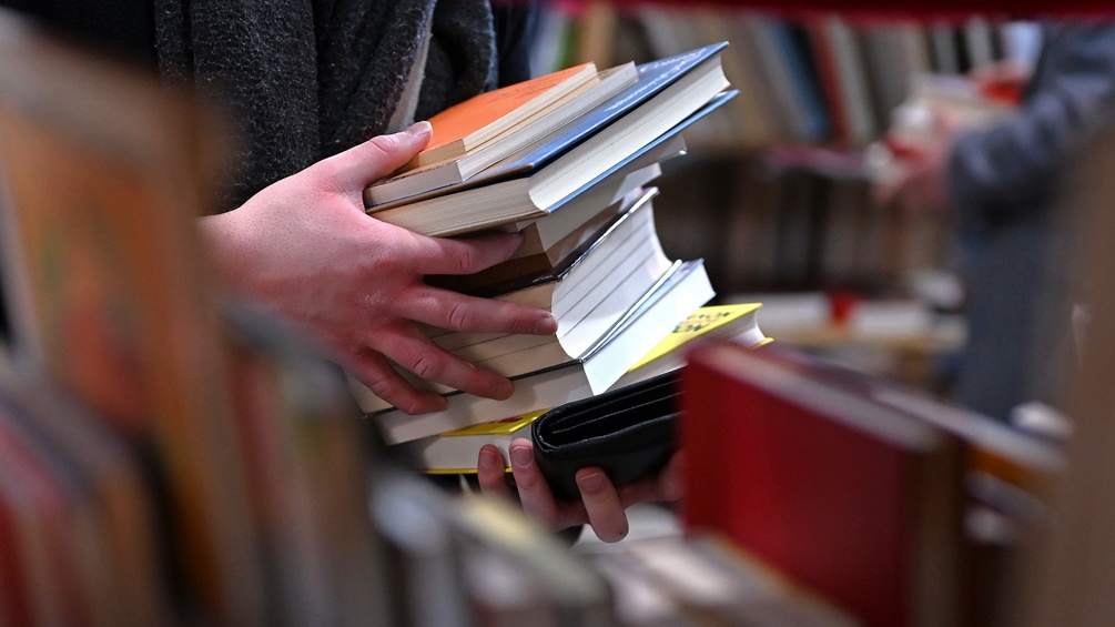 Eine Person hält einen Buchstapel in Händen auf der Leipziger Buchmesse