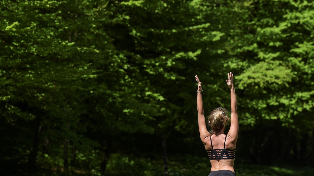Eine Frau übt Yoga aus und streckt die Arme hoch