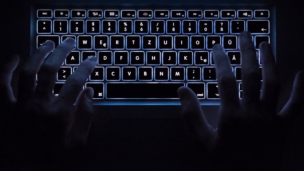 Ein Paar Hände auf einer Computertastatur im Dunkeln
